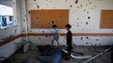 Zwei Kinder stehen in einem Klassenzimmer einer von der UN betriebenen Schule im Flüchtlingscamp Al Maghazi im Gazastreifen. Die Wände sind von Schrapnell-Einschlägen gezeichnet.