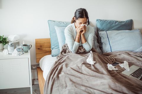 Frau liegt mit Tempos und Corona im Bett