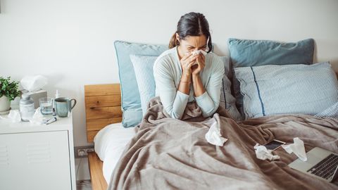 Frau liegt mit Tempos und Corona im Bett