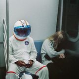 Ein an Halloween als Astronaut verkleideter Mann sitzt neben einem sich versteckenden Mädchen in der U-Bahn in NewYork
