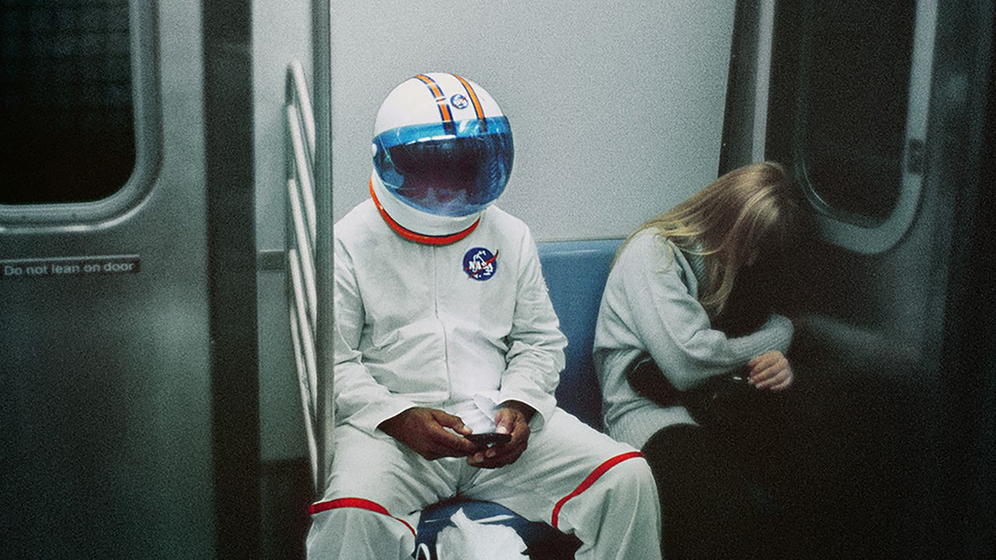 Ein an Halloween als Astronaut verkleideter Mann sitzt neben einem sich versteckenden Mädchen in der U-Bahn in NewYork Ein an Halloween als Astronaut verkleideter Mann sitzt neben einem sich versteckenden Mädchen in der U-Bahn in NewYork