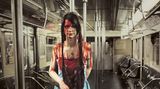 Eine zu Halloween verkleidete Frau im Kostüm "Carrie" Blutverschmiert mit blauem Kleid, Krönchen und einem Strauß Rosen