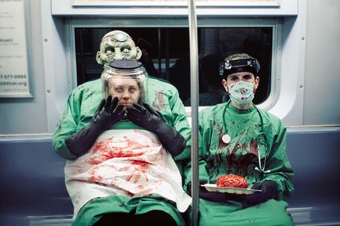 Zwei Menschen mit Halloweenverkleidung als Blutüberströmte Ärzte sitzen in der U-Bahn in New York