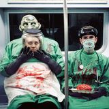 Zwei Menschen mit Halloweenverkleidung als Blutüberströmte Ärzte sitzen in der U-Bahn in New York