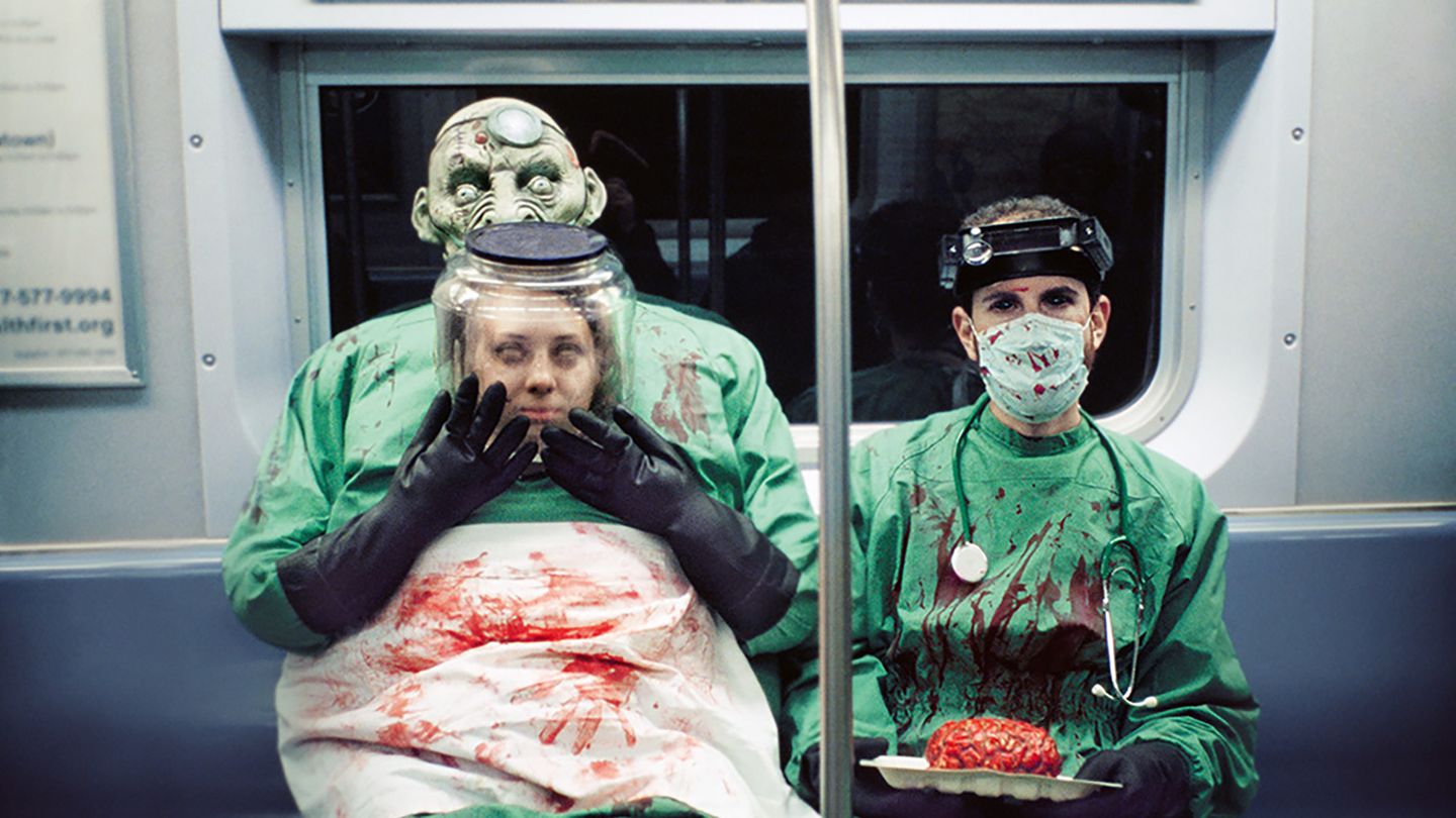 Zwei Menschen mit Halloweenverkleidung als Blutüberströmte Ärzte sitzen in der U-Bahn in New York