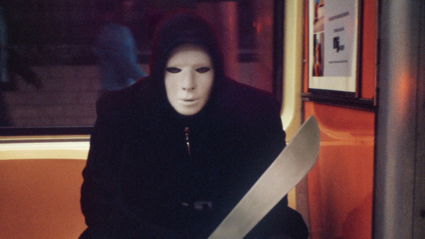 Ein Mann mit Maske und einem großen unechten Messer sitzt als Swordsman verkleidet an Halloween in einer New Yorker U-Bahn