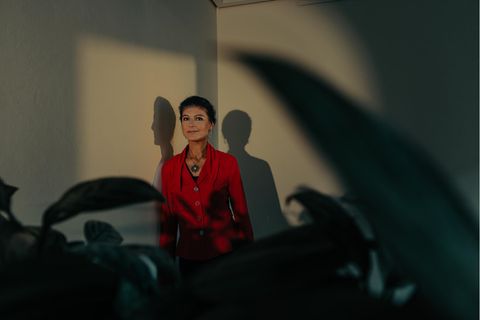 Sahra Wagenknecht, 54, lehnt an einer Wand, vor ihr Pflanzen