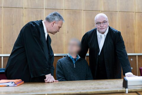 Der Angeklagte sitzt vor Verhandlungsbeginn in einem Gerichtssaal im Landgericht Hannover. Daneben stehen seine Anwälte