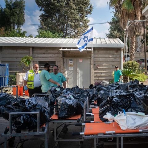 Zahlreiche Leichensäcke liegen aufgereiht vor einer Israel-Flagge
