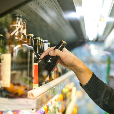 Ein Mann in einem Supermarkt nimmt eine Bierflasche aus dem Regal