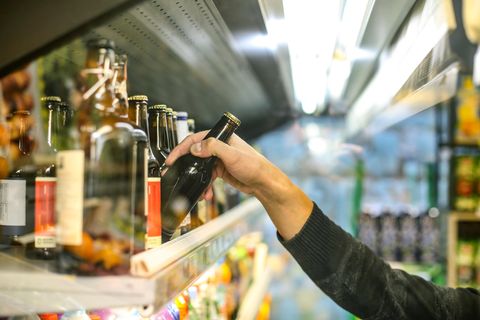 Ein Mann in einem Supermarkt nimmt eine Bierflasche aus dem Regal