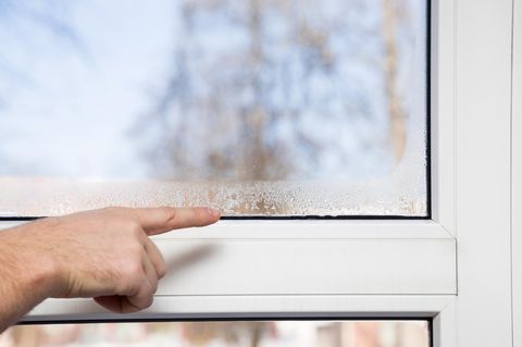Person zeigt auf Fenster, das durch zu hohe Luftfeuchtigkeit beschlagen ist