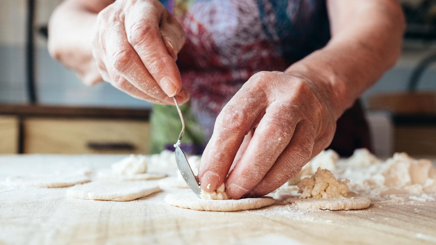 Die Hände einer älteren weißen Frau füllen Pasta