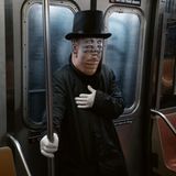 Ein Mann steht an Halloween mit einer Vertigo Maske in einer NewYorker U-Bahn