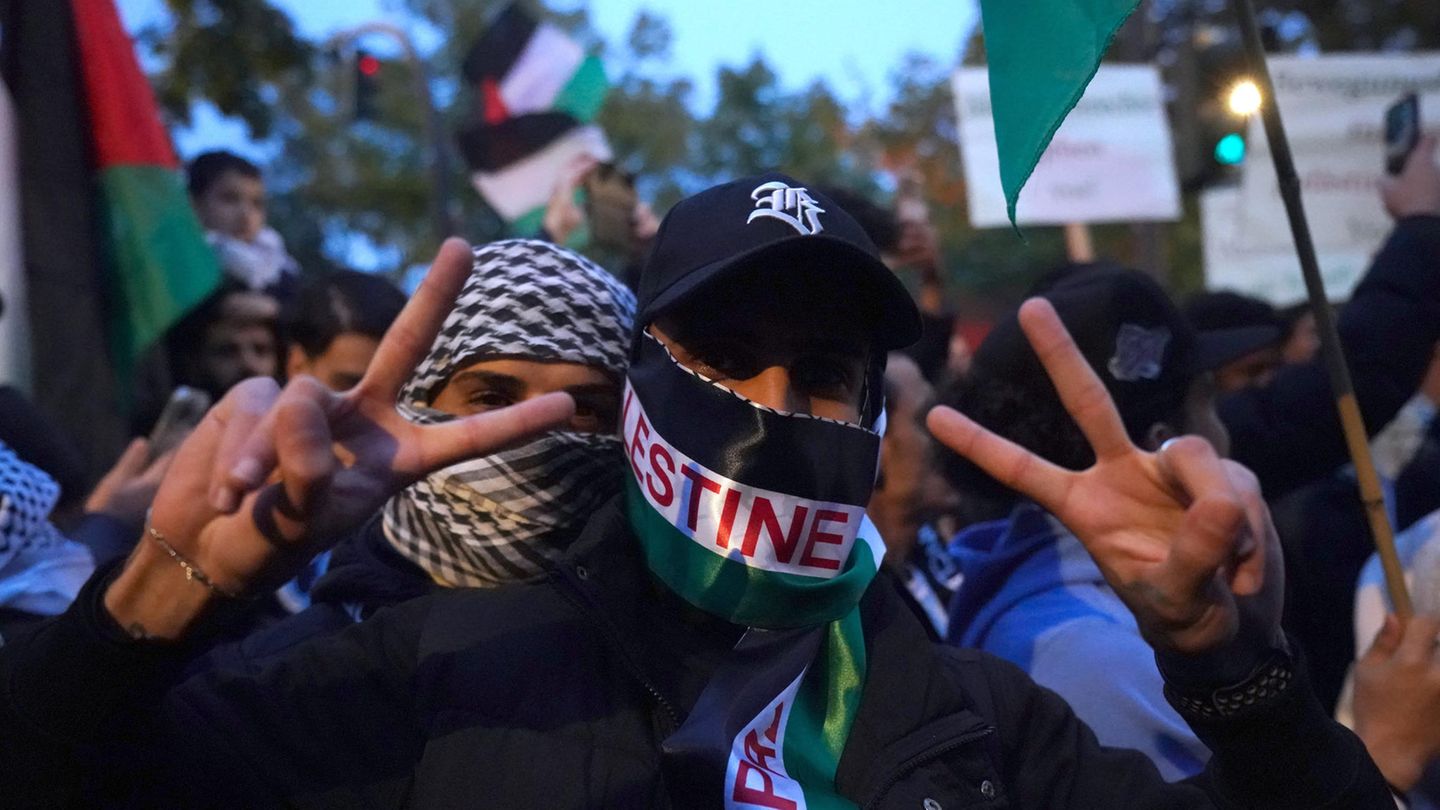 Ein vermummter Teilnehmer einer pro-palästinensischen Demo in Hamburg zeigt mit beiden Händen ein Victory-Zeichen