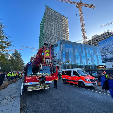 Einsatzfahrzeuge der Feuerwehr stehen vor einem eingerüsteten Hochhaus in Hamburg