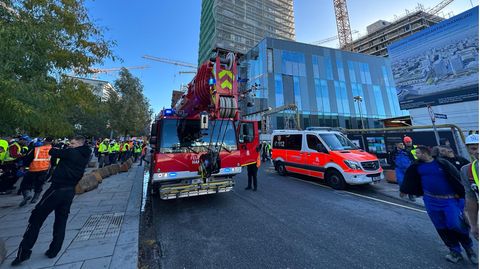 Einsatzfahrzeuge der Feuerwehr stehen vor einem eingerüsteten Hochhaus in Hamburg