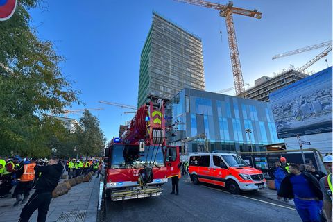 Einsatzfahrzeuge der Feuerwehr stehen vor einem eingerüsteten Hochhaus in Hamburg