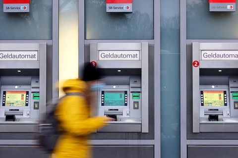 Eine Frau geht an Geldautomaten vorbei