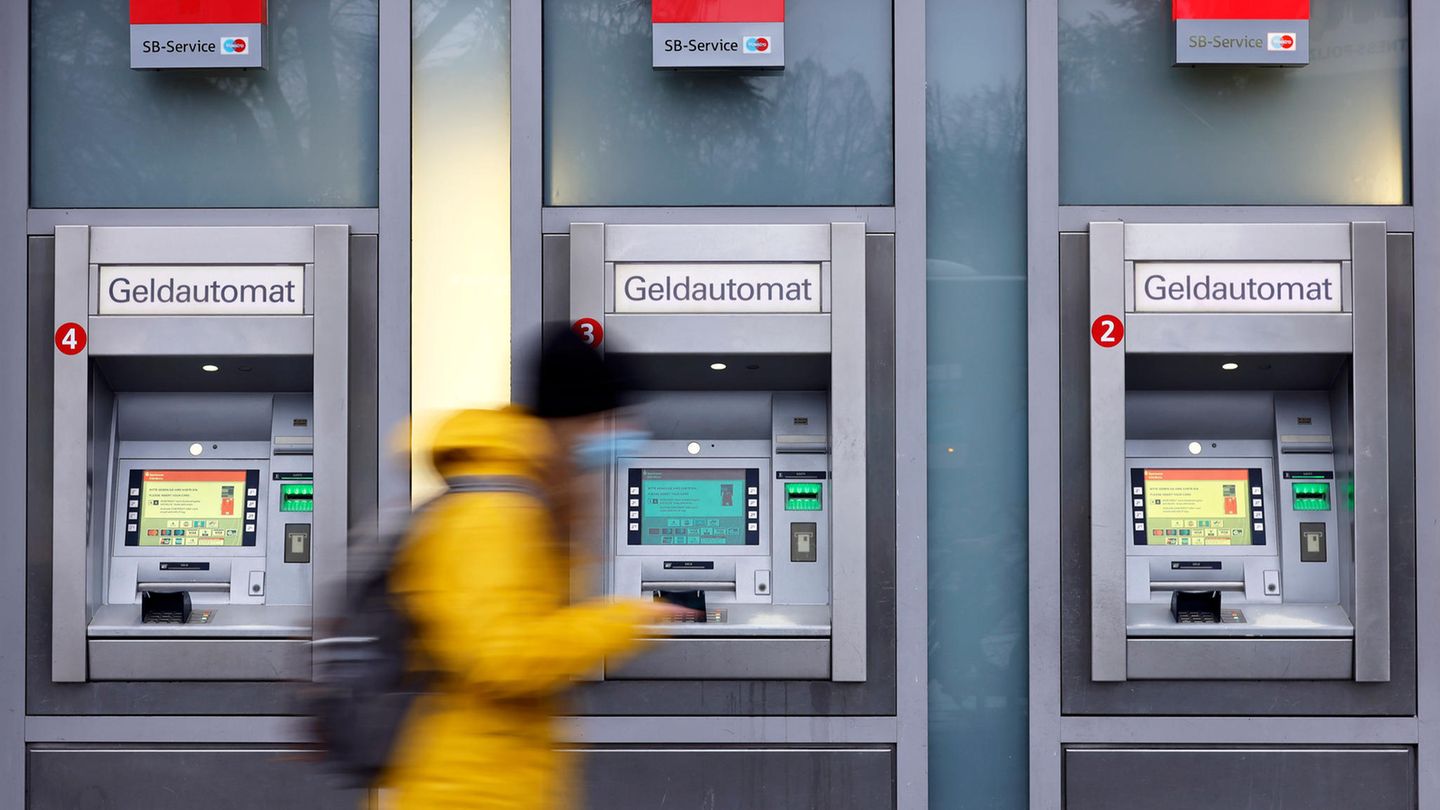 Eine Frau geht an Geldautomaten vorbei