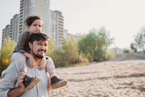 Studie: Ein junger Vater trägt einen Jungen auf den Schultern
