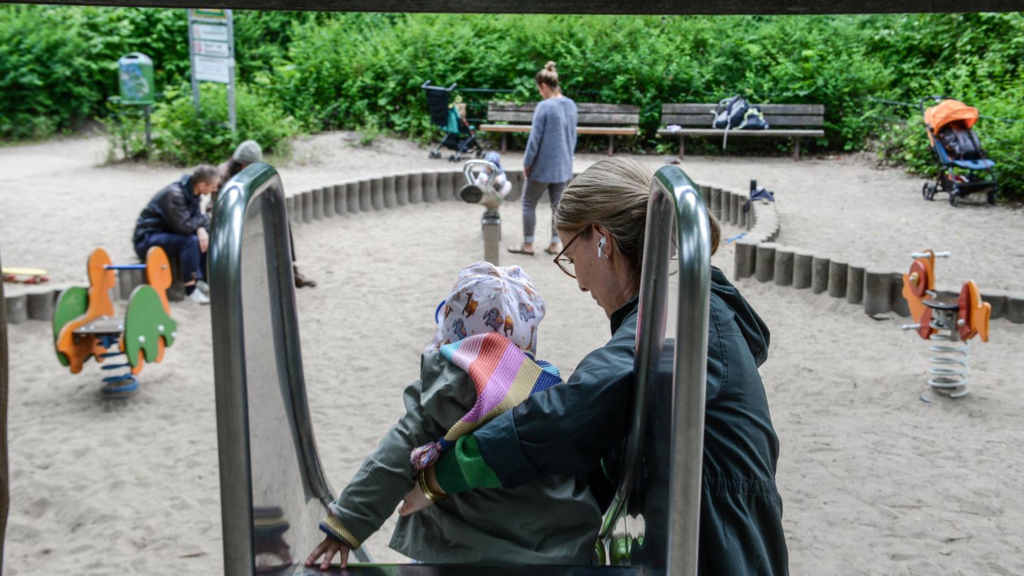 Frau hilft kleinem Mädchen auf einer Rutsche