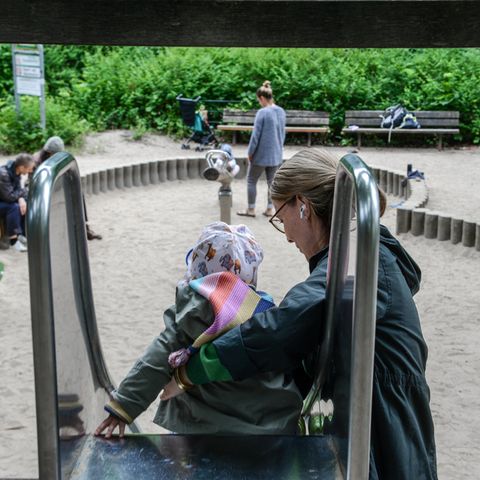 Frau hilft kleinem Mädchen auf einer Rutsche