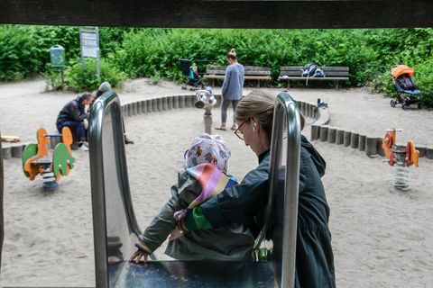 Frau hilft kleinem Mädchen auf einer Rutsche