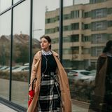 Frau in Mantel und mit kariertem Rock