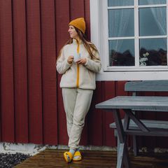 Reisende, die eine morgendliche Tasse Kaffee von rotem Rorbu auf den Lofoten genießt