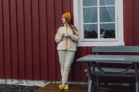 Reisende, die eine morgendliche Tasse Kaffee von rotem Rorbu auf den Lofoten genießt