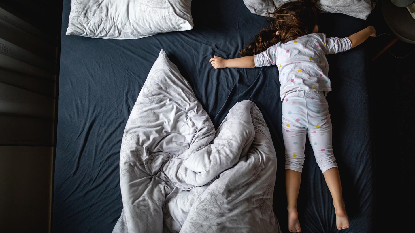 Ein kleines Kind liegt auf einem großen Bett