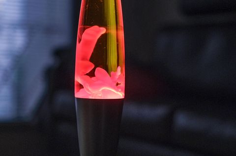 Eine Lavalampe leuchtet rot in einem abgedunkelten Zimmer.