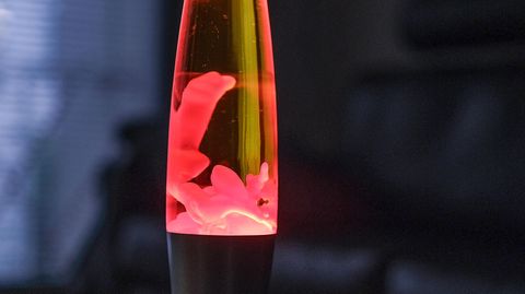 Eine Lavalampe leuchtet rot in einem abgedunkelten Zimmer.