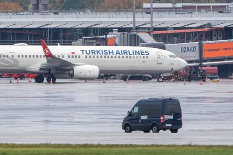 Ein Polizeifahrzeug steht auf dem Flughafen vor einem Flugzeug, an dem ein Auto mit einem Geiselnehmer steht