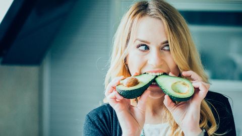 Frau isst Avocado