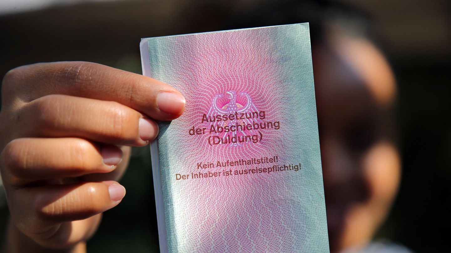 Eine Frau mit afrikanischen Wurzeln hält eine Duldung in die Kamera