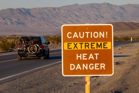 Ein Auto fährt an einem Schild im Death Valley National Park vorbei, das vor extremer Hitze warnt