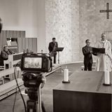 Priester, Orgelspieler, Saxophonspieler und Helfer nehmen Gottesdienst mit Kamera auf
