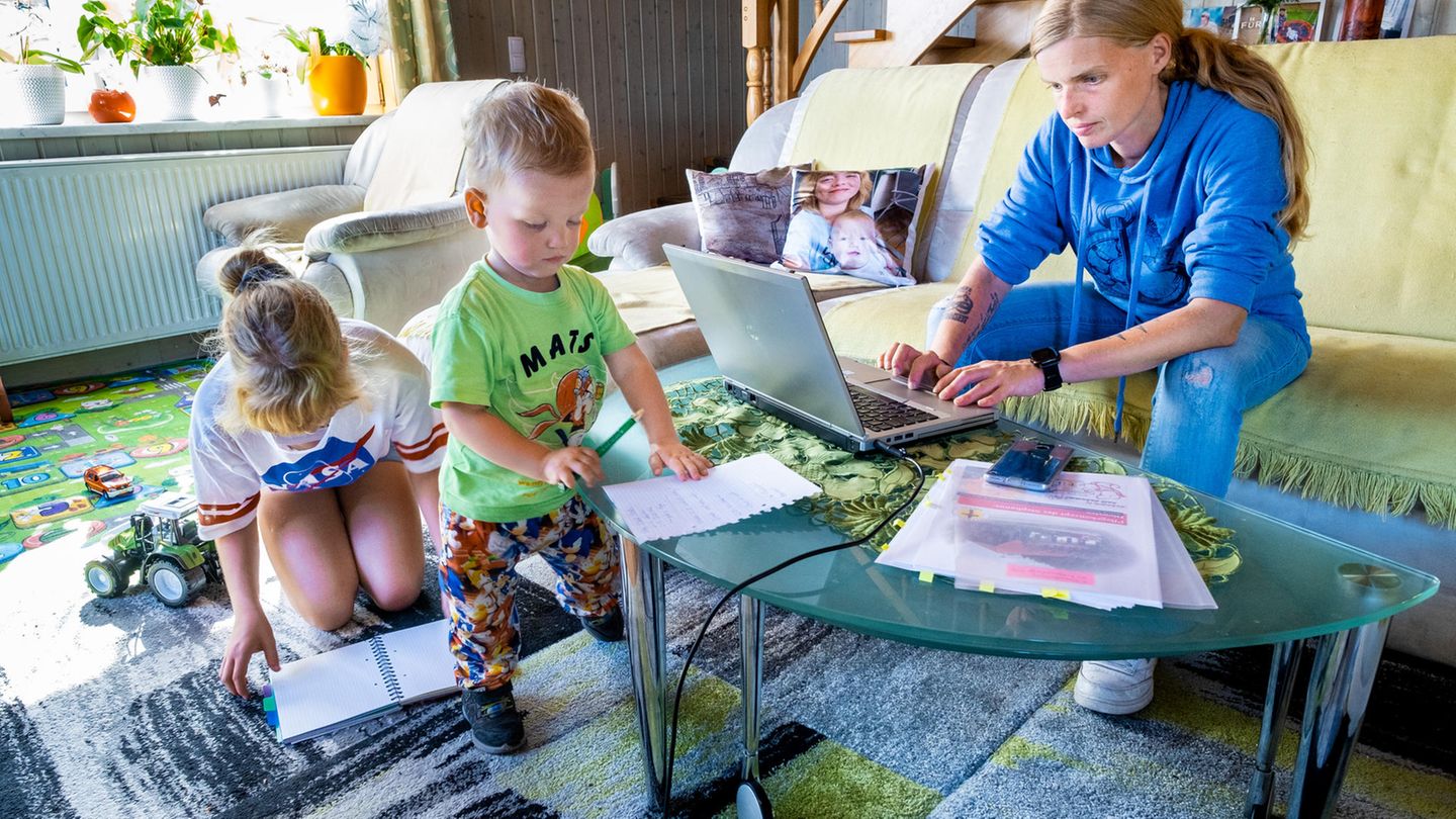 Frau arbeitet am Laptop, daneben zwei kleine Kinder