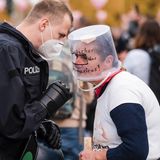 Frau mit "Eimermaske" diskutiert mit einem Polizisten