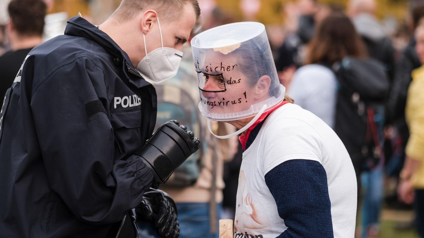 Frau mit "Eimermaske" diskutiert mit einem Polizisten