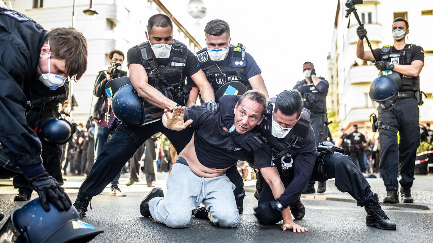 Mann am Boden umgeben von mehreren Polizisten