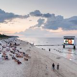 Menschen in Liegestühlen am Strand gucken Kinofilm