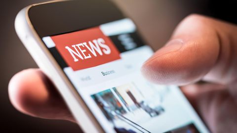 Medienkonsum: Ein Mann hält ein Smartphone in der Hand und liest Nachrichten