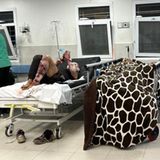 Auch auf dieser Station sieht es nicht besser aus. Ein schwerverletzter Patient liegt mit blutigen Verbänden im Bett, andere haben sich auf dem Boden zusammengekauert.