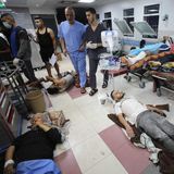 Kriegsalltag in der Klinik: Auf einer überfüllten Station sehen Ärzte nach ihren Patienten. Weil die Betten knapp sind, müssen viele mit dem Fliesenboden Vorlieb nehmen.