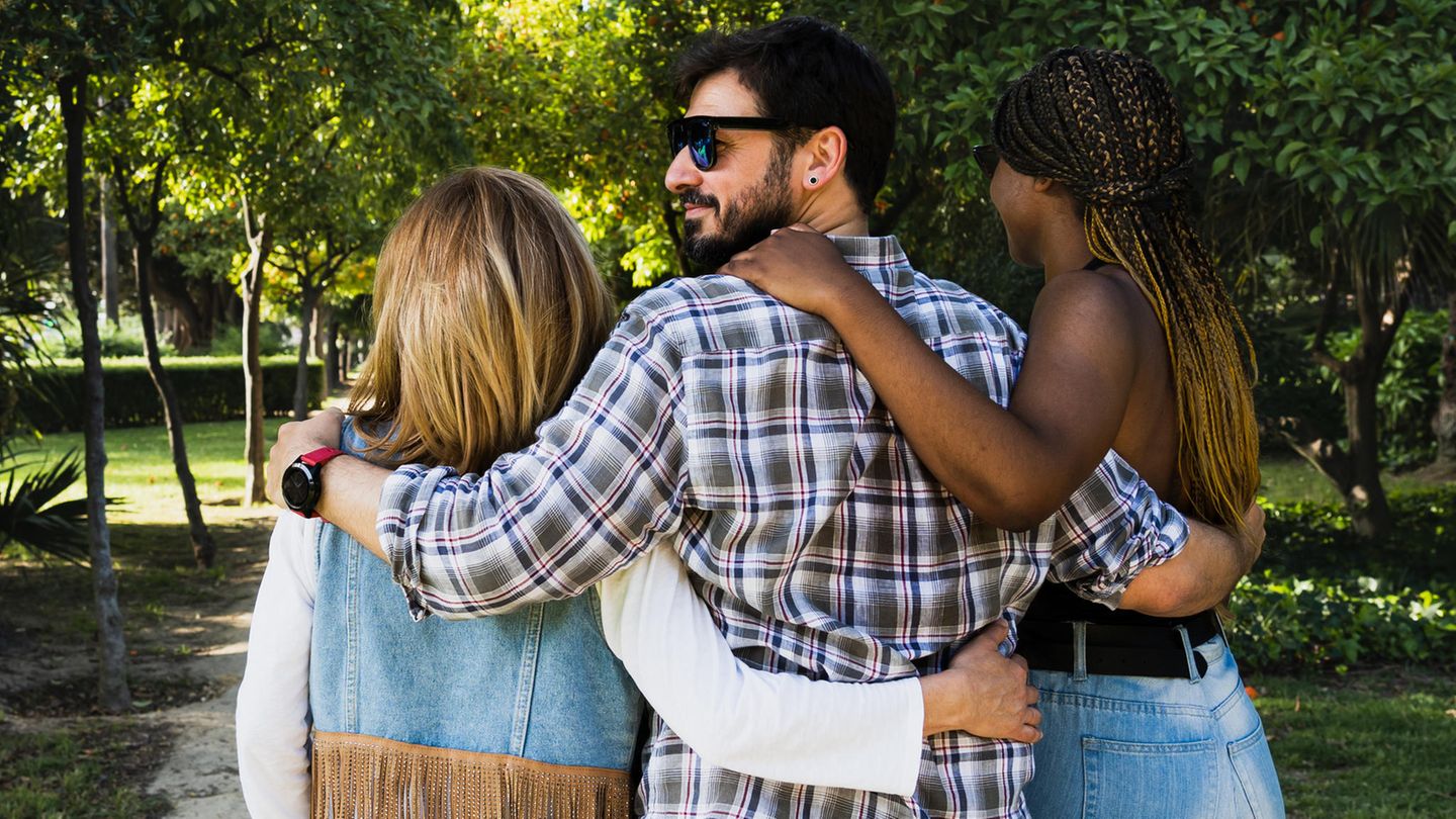 Ein Mann geht in den Armen zweier Frauen spazieren