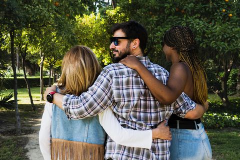 Ein Mann geht in den Armen zweier Frauen spazieren