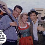 Hannelore Auer steht zwischen zwei Männern mit Gitarre